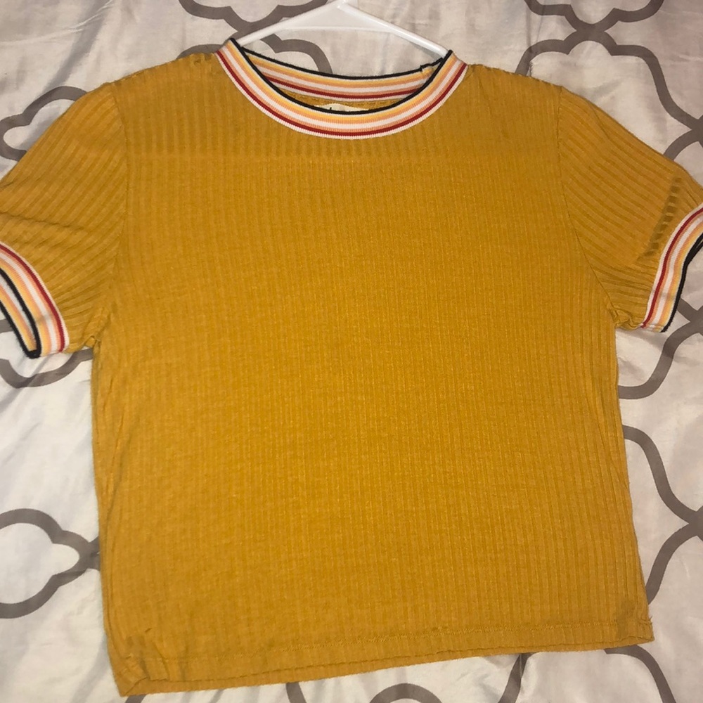 A yellow shirt w/ colorful stripes on the sleeves